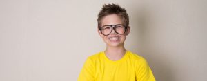 lachende jongen met geel t-shirt en bril