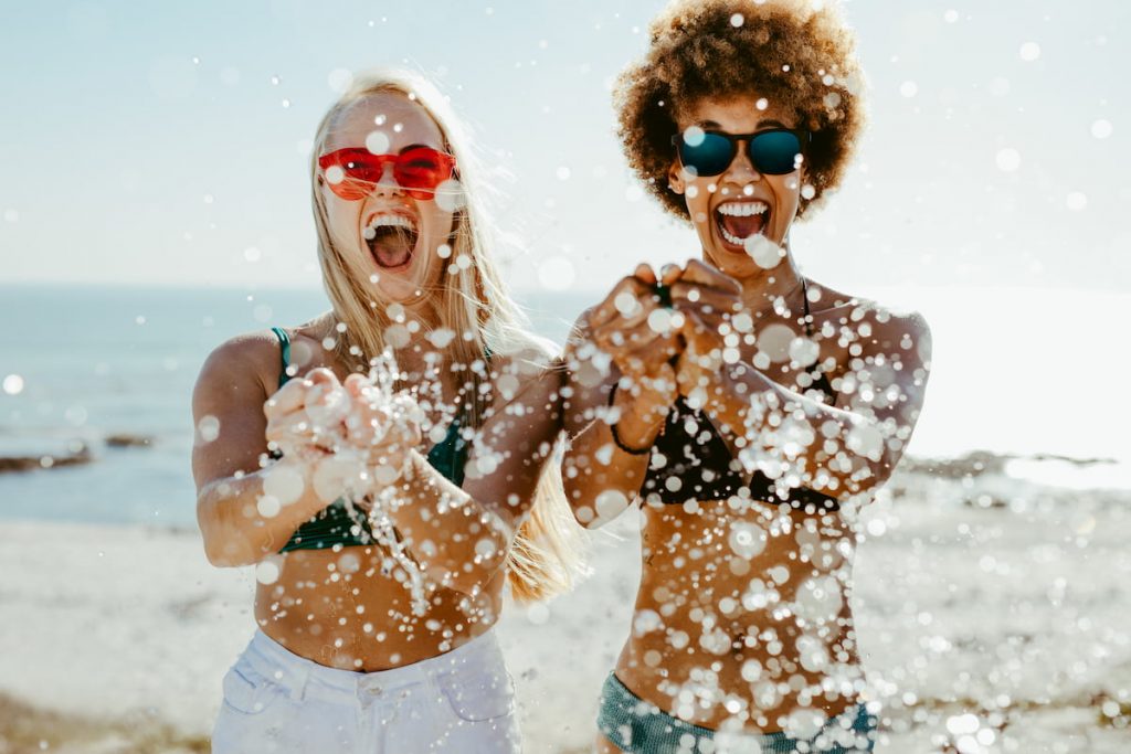 2 dames dragen zonnebrillen op het strand tijdens vakantie