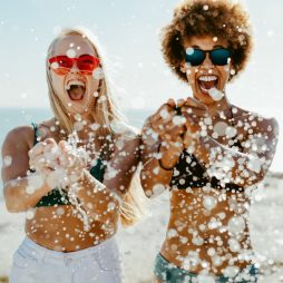 2 dames dragen zonnebrillen op het strand tijdens vakantie